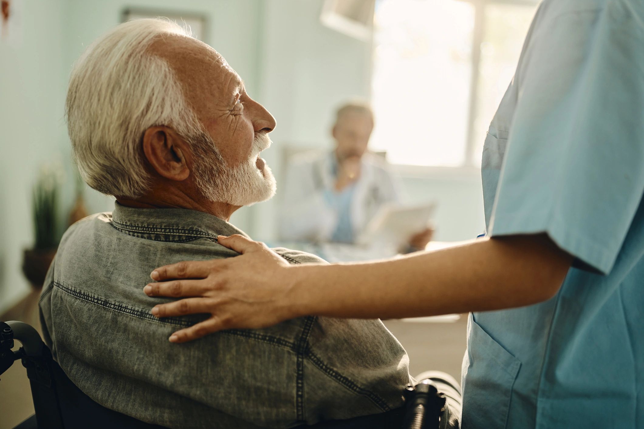 Senior patient in wheelchair speaking with a nurse