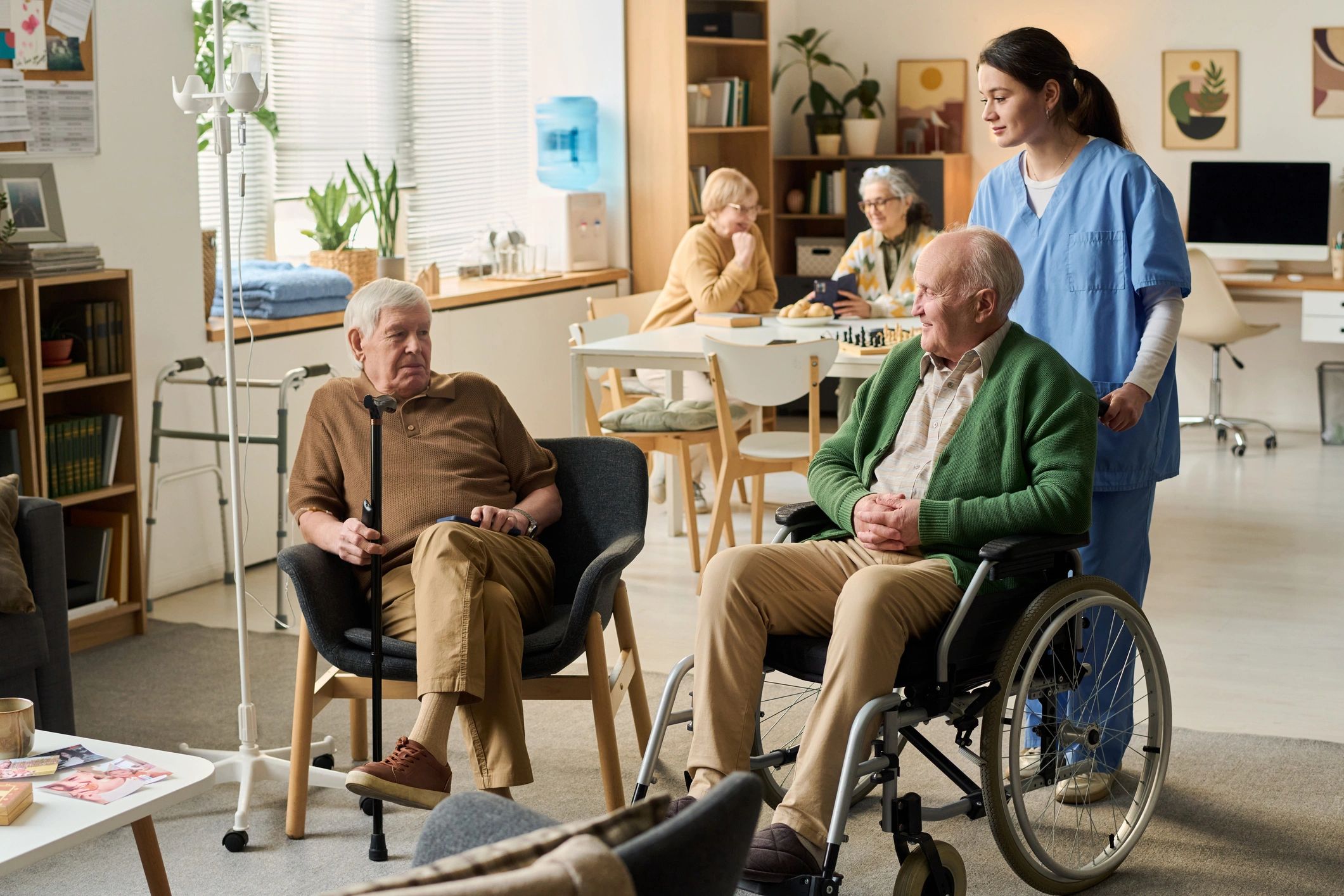 Caregiver assisting residents in a welcoming nursing home common area